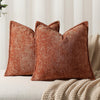 A close-up of a textured, rust-colored chenille throw pillow in a modern farmhouse style.