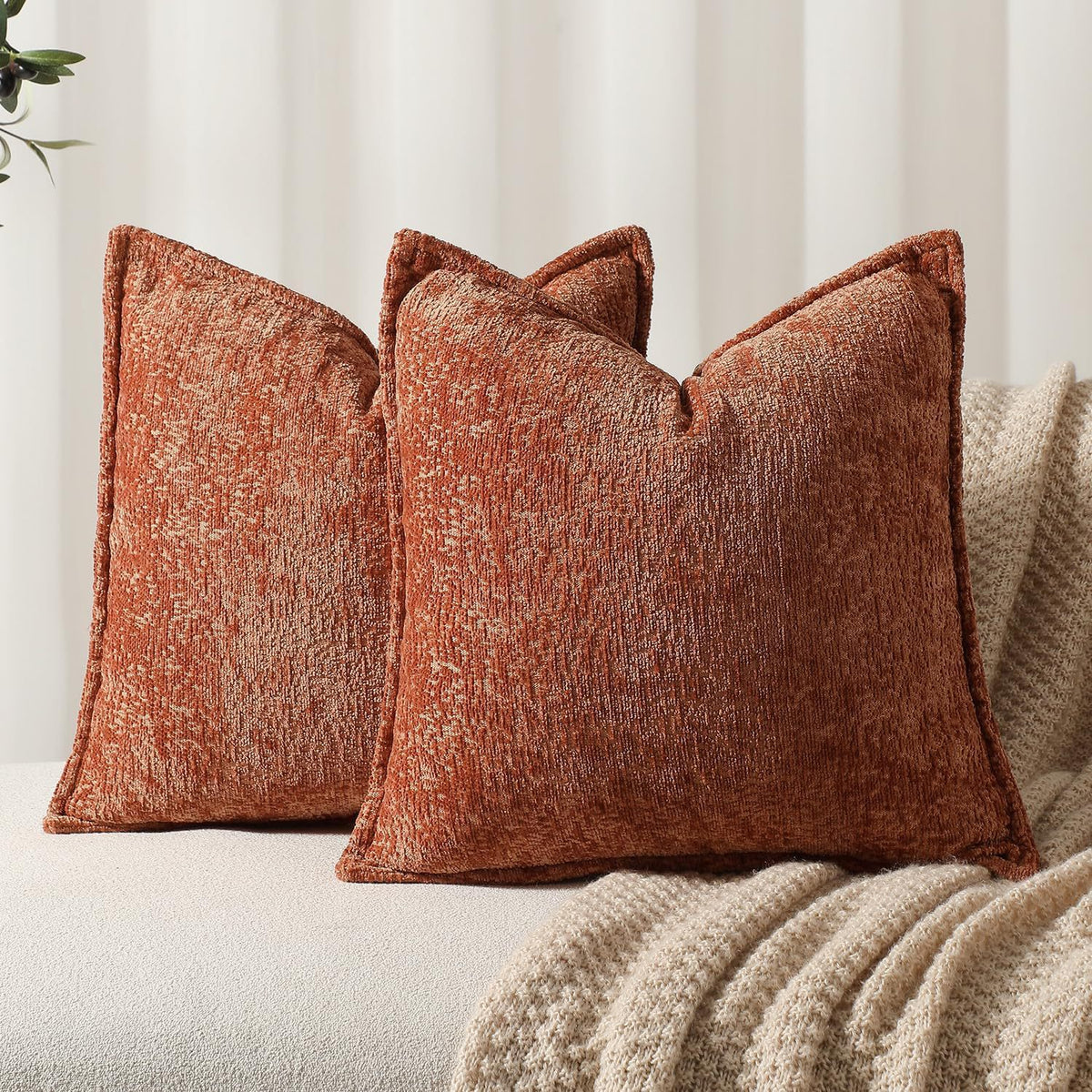 A close-up of a textured, rust-colored chenille throw pillow in a modern farmhouse style.
