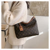 A woman holds a brown leather tote bag with a gold chain strap and a flap closure against a light background.