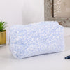 A light blue leopard print cosmetic bag with a plush lining resting on a white surface.