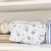 A white cosmetic pouch with a vintage rose print and lace trim resting on a white shelf.