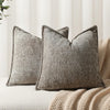 A close-up of a textured gray chenille throw pillow cover resting on a beige knitted blanket.