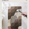 A hand is pouring water from a metal faucet onto a brown and beige kitchen mat, demonstrating the product's function.