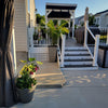 A set of solar post cap lights with warm LED illuminating a white fence and deck area.
