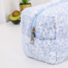 A light blue leopard print cosmetic bag with a plush, fluffy lining and a silver zipper detail.