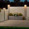 A white wooden fence illuminated by solar post cap lights with warm LED for a backyard patio.