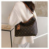 A beige knit sweater sleeve shows a brown leather tote bag with a gold hardware detail.