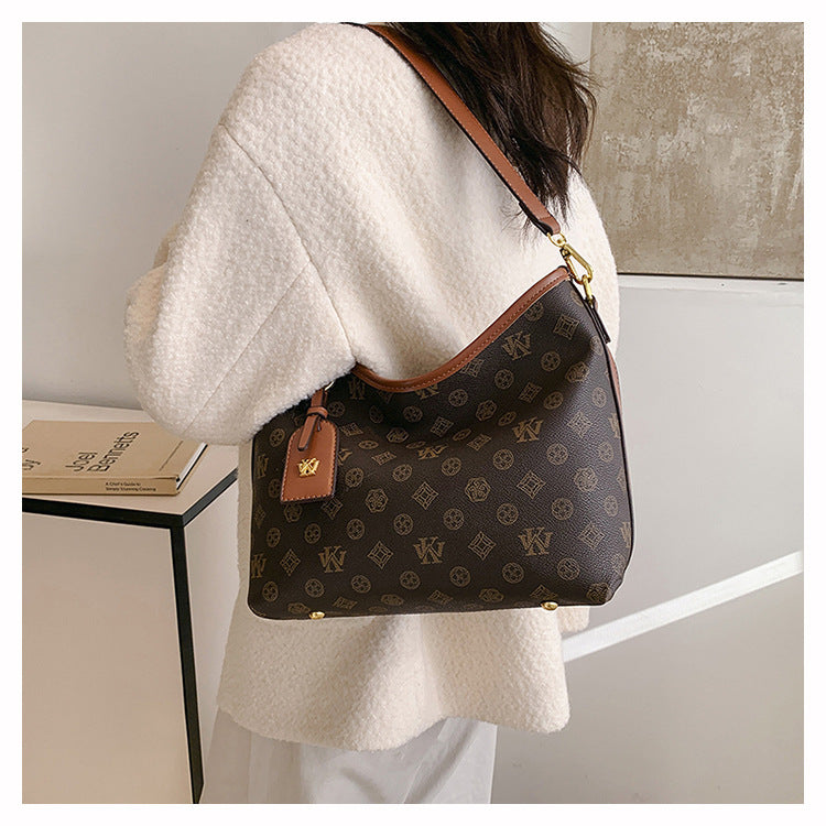 A beige knit sweater sleeve shows a brown leather tote bag with a gold hardware detail.