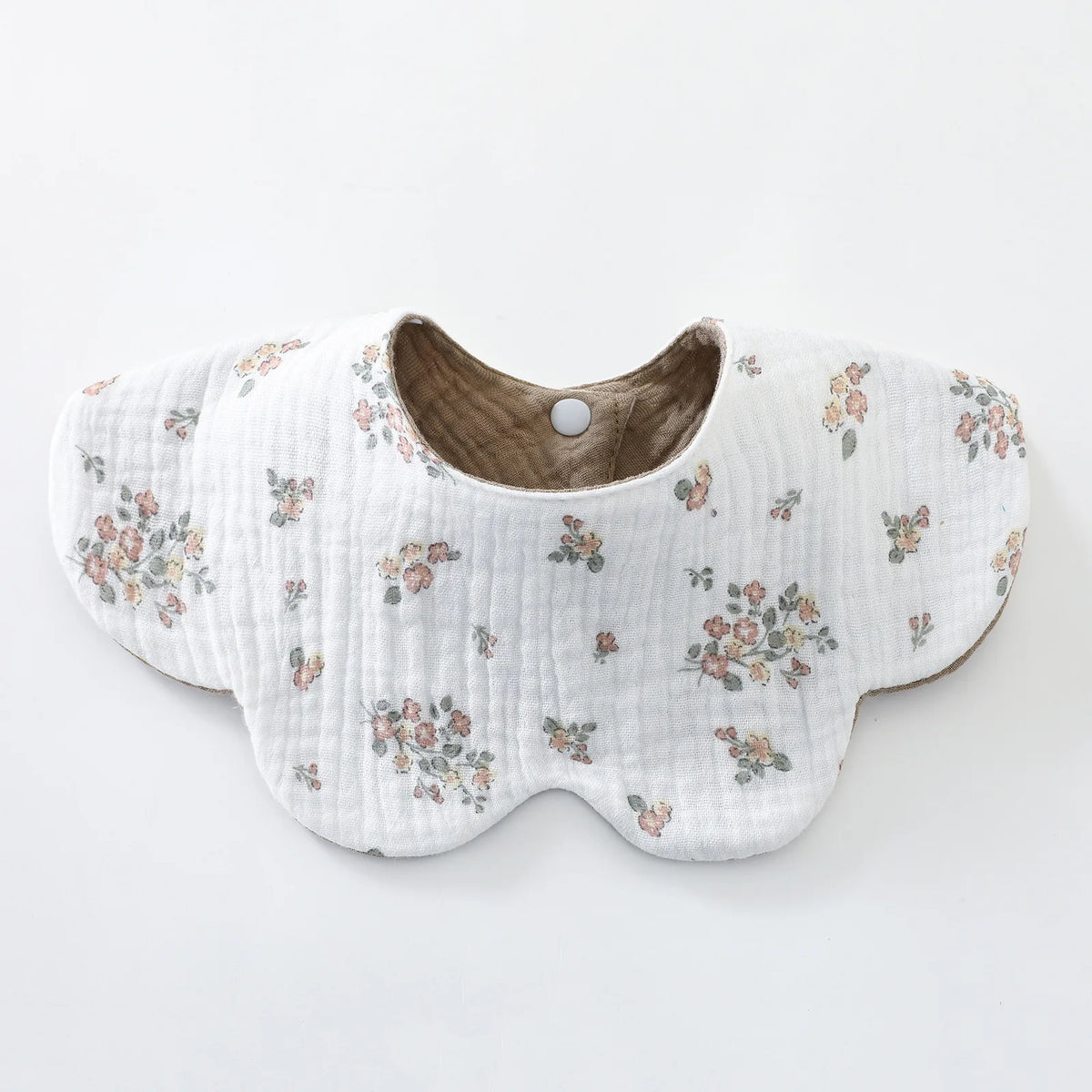 White quilted baby feeding bib with a floral print and brown trim