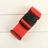 A bright orange woven strap with a black buckle used for luggage security.