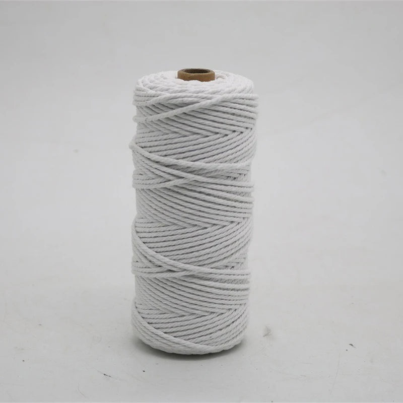 A spool of white macrame cord, made of 100% cotton, measuring 3mm/4mm thickness and 100 meters long for crafting.