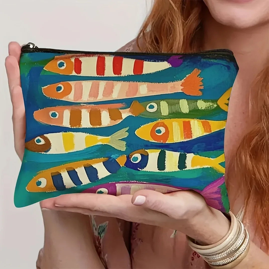 A hand holds a vintage sardine print canvas cosmetic bag featuring colorful fish designs.