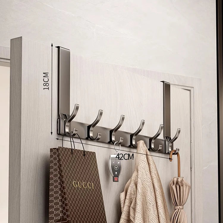 A silver over-the-door organizer rack with eight hooks mounted on a light gray wall.