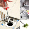 A hand uses a flexible drain snake to clear a clog in a kitchen sink, showing the tool and the removed hair.