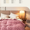 A pink quilted duvet cover and blanket displayed on a bed with soft lighting.