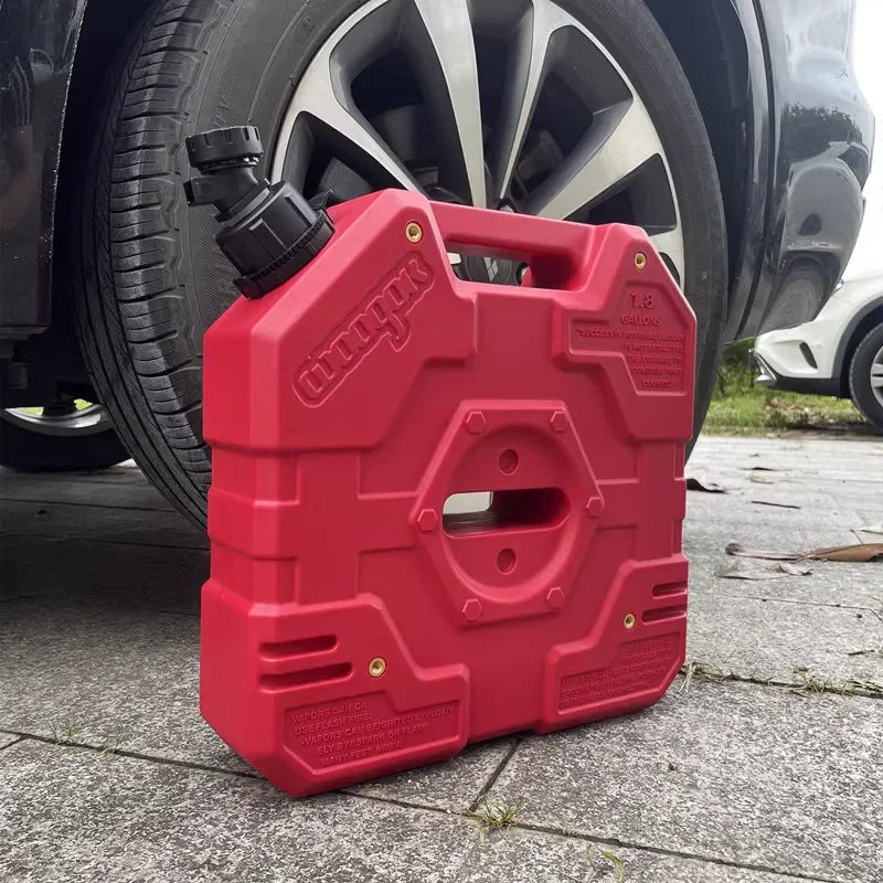 A red universal water tap faucet adapter is shown resting on a concrete surface next to a car tire and wheel.