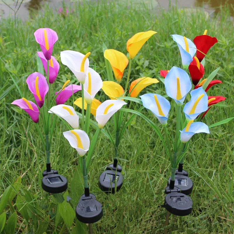A set of solar-powered calla lily LED garden lights growing in green grass.