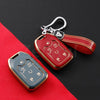 A red key fob cover with a silver keychain attached, resting on a red fabric background.