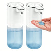 A white and blue touchless automatic soap dispenser with a pump mechanism is held in a hand.