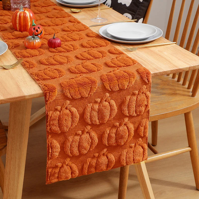 Orange textured table runner with pumpkin designs set on a wooden table.