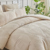 A beige embossed leaf pattern microfiber duvet cover set displayed on a bed with green foliage in the background.