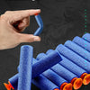 A hand holds a blue soft bullet from an electric gatling gun toy, demonstrating its use on a dark surface.