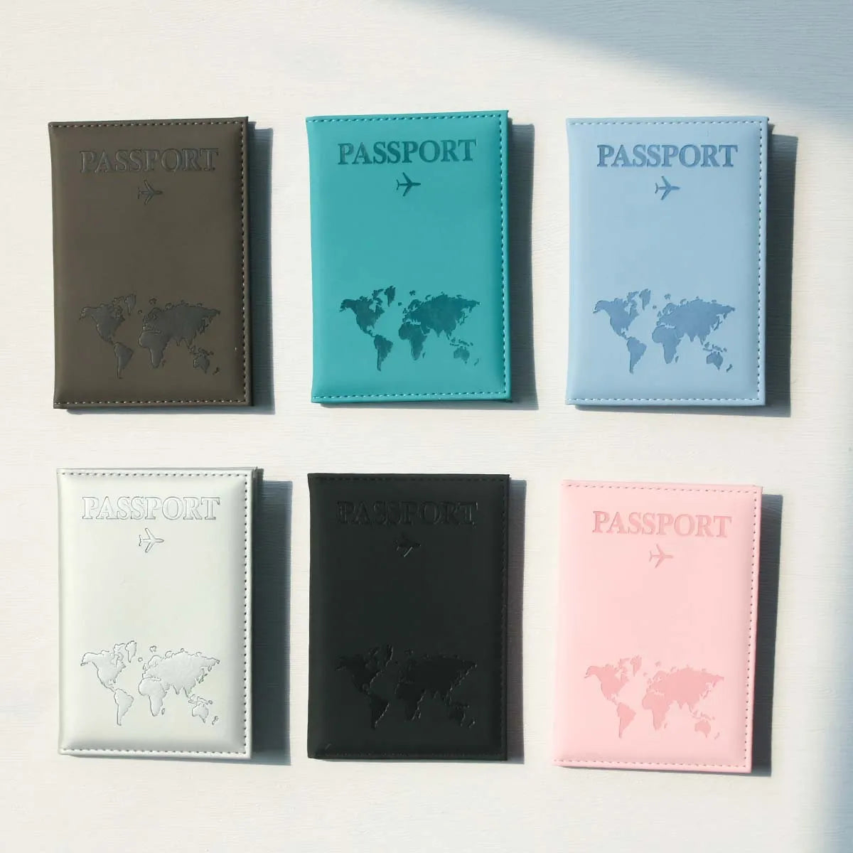Eine Sammlung von fünf schlanken Reisepasshüllen in verschiedenen Farben darunter braun, türkis, hellblau, schwarz und rosa.