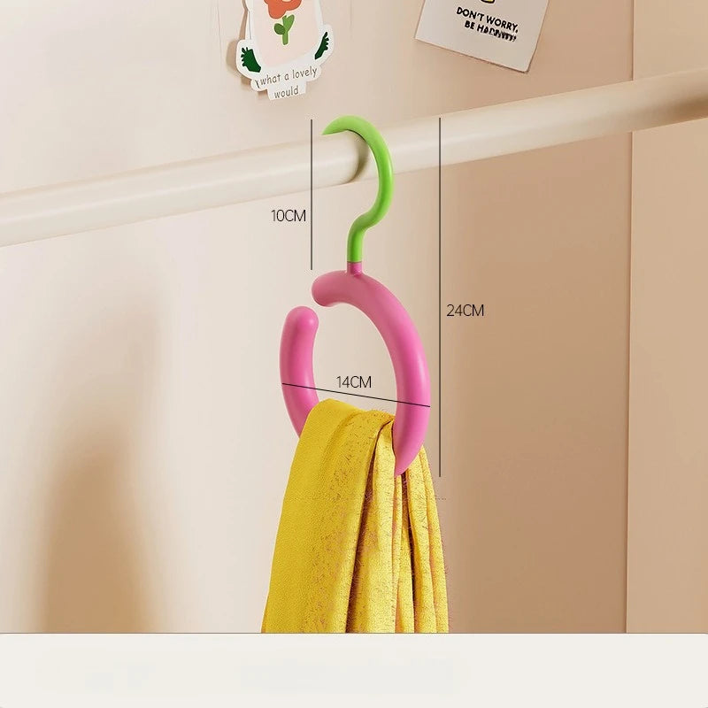 A pink and green wall-mounted hook organizer for hanging a yellow scarf or hat.