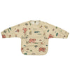 A beige waterproof long-sleeve smock for toddlers featuring a colorful pattern of animals and nature elements.