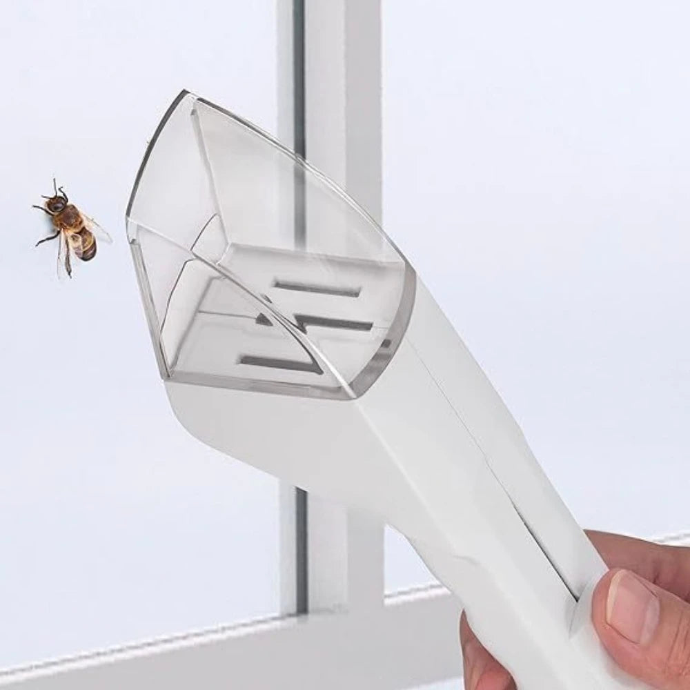 A hand holds a white handheld insect catcher with a telescopic handle, positioned near a window.