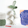 A white crochet kit featuring a cute animal and plant project, including yarn and tools.