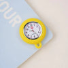 A yellow silicone pocket watch with a silver face and black hands is shown on a light blue background.