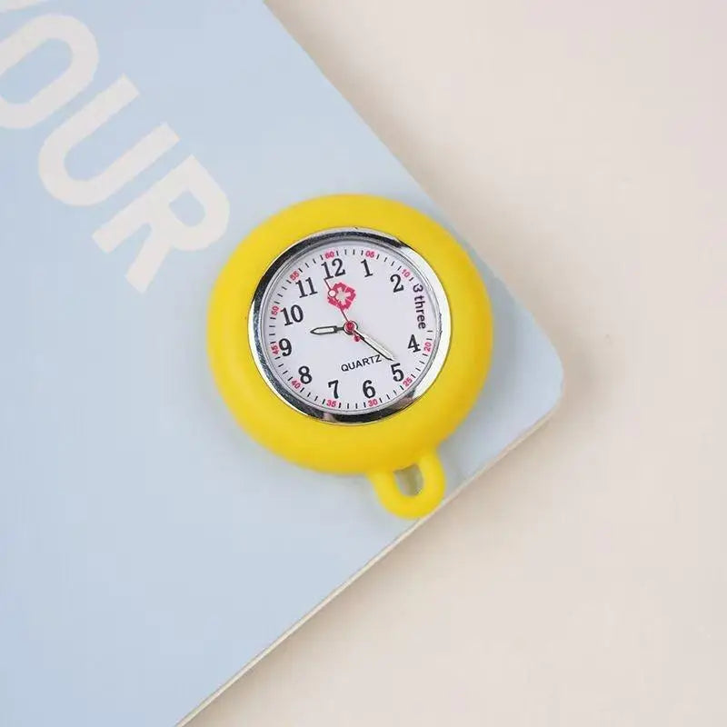 A yellow silicone pocket watch with a silver face and black hands is shown on a light blue background.