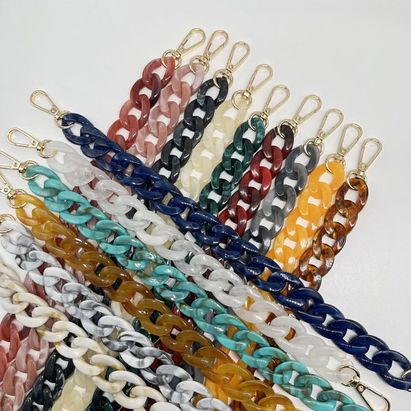 A collection of vibrant multicolor acrylic bag chains and shoulder straps in various colors like pink, black, white, and yell