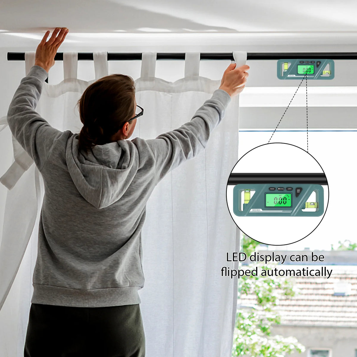 A person is adjusting a window blind with a digital magnetic inclinometer that has an LED display.