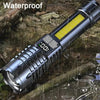 A silver high-power LED flashlight with a yellow light strip is shown being used in wet, outdoor conditions.