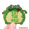 An embroidered patch featuring a green cartoon frog with a red tongue, with the text Eat The Rich.
