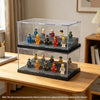 A clear acrylic display case holds various miniature figurines and collectibles on a wooden table.
