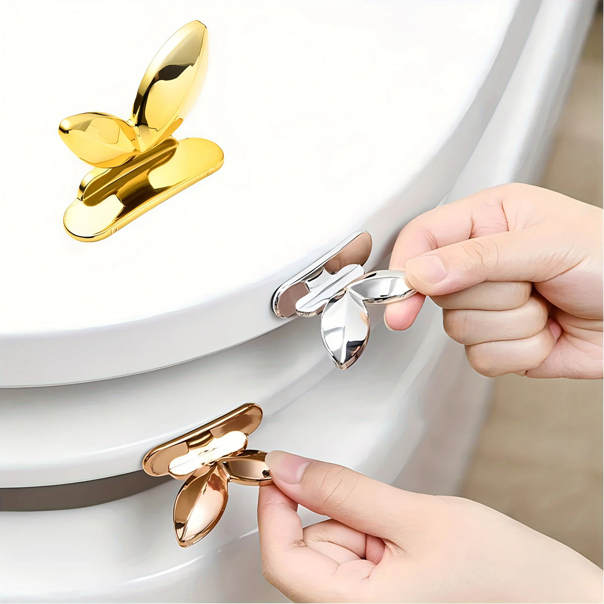 A hand is lifting a gold-colored touch-free toilet seat lifter from a white toilet bowl.