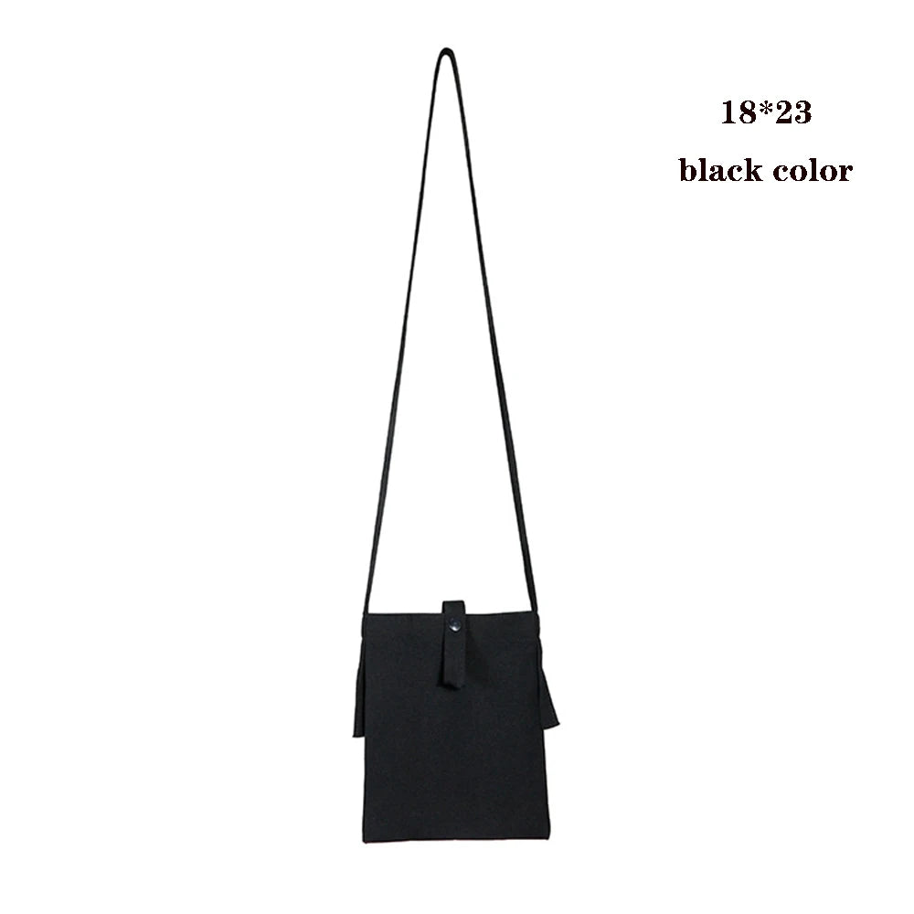 Black foldable canvas tote bag with a long strap shown against a white background.