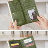A close-up display of a green leather vintage kiss lock long wallet being held by a hand.
