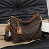 A brown leather tote bag with a monogram pattern rests on a black leather surface.