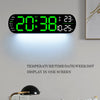 A large digital wall clock displaying time, date, temperature, and day of the week on a white wall.