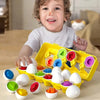 A toddler is interacting with a yellow plastic sorting puzzle containing various colored egg-shaped pieces.