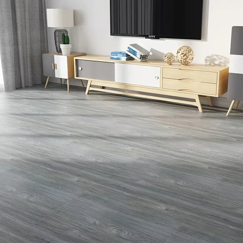Light gray wood grain vinyl flooring tiles installed in a modern living room setting.