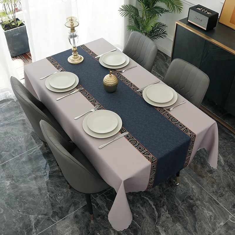 A long dining table set with a gray tablecloth, white plates, and silverware in a modern interior.
