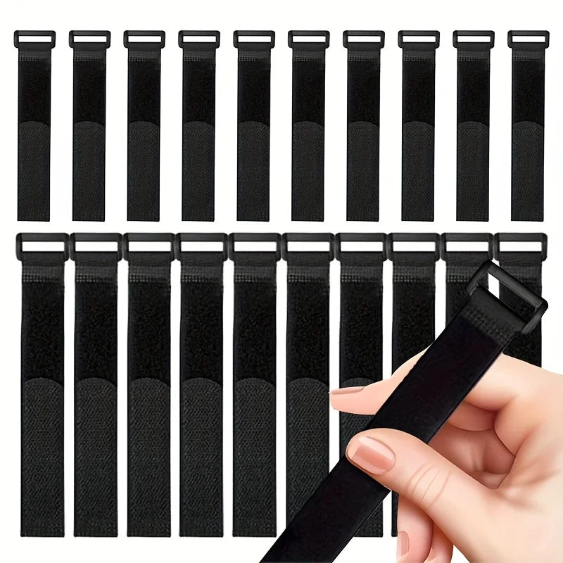 A collection of black reusable nylon cable ties with adjustable hook and loop fasteners shown next to a hand.