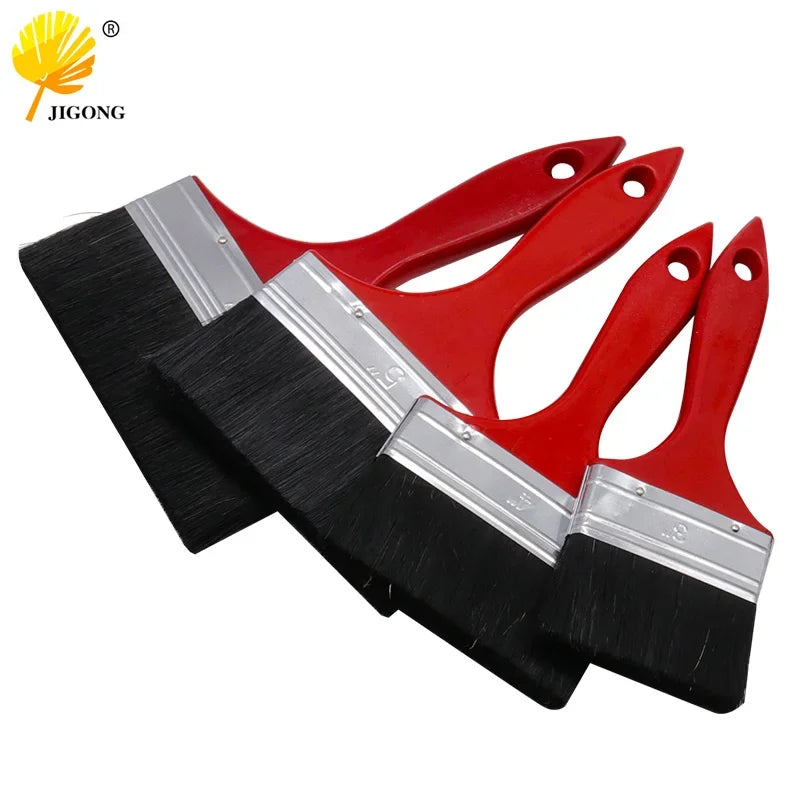 A set of versatile paint brushes with red plastic handles and black bristles shown diagonally.