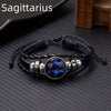 A black leather wrap bracelet featuring a glowing purple and blue zodiac constellation charm.
