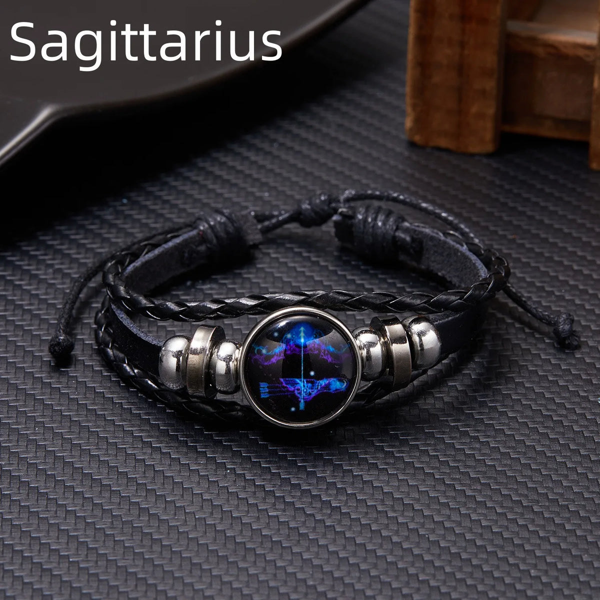 A black leather wrap bracelet featuring a glowing purple and blue zodiac constellation charm.